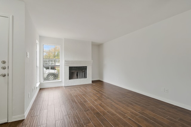 unfurnished living room featuring dark hardwood / wood-style flooring and a brick fireplace