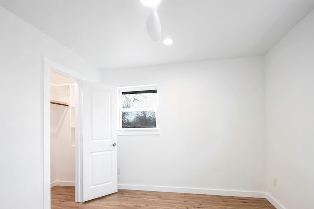 unfurnished bedroom featuring wood-type flooring, a spacious closet, and a closet