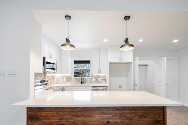 kitchen with tasteful backsplash, sink, stainless steel appliances, and decorative light fixtures