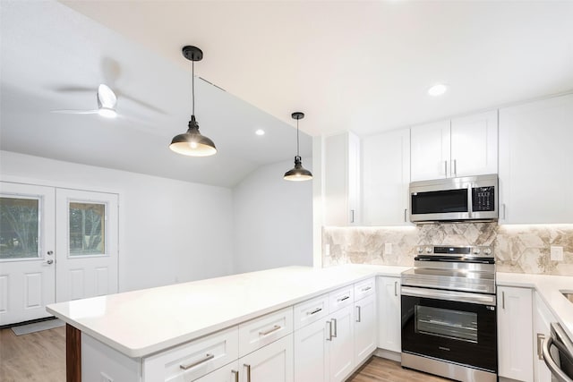 kitchen featuring kitchen peninsula, white cabinetry, stainless steel appliances, and decorative light fixtures