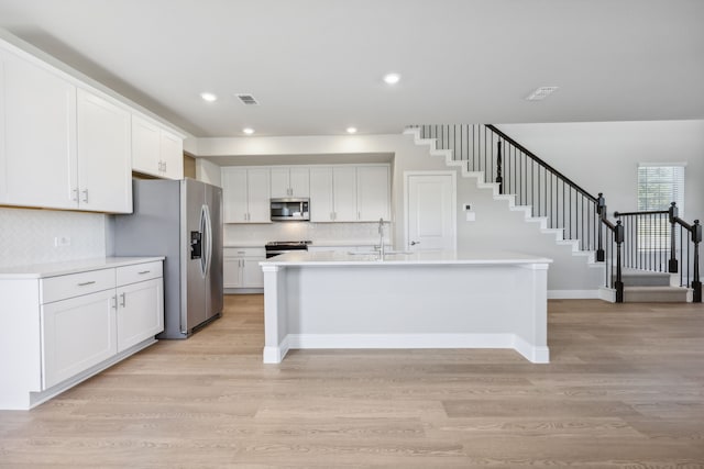 kitchen with sink, stainless steel appliances, light hardwood / wood-style floors, a center island with sink, and white cabinets