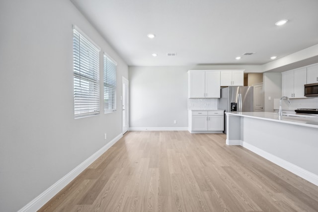 kitchen with decorative backsplash, stainless steel appliances, sink, light hardwood / wood-style flooring, and white cabinets