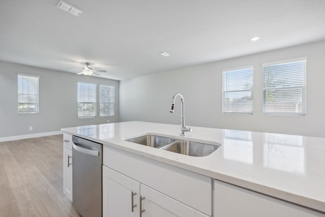 kitchen with light stone countertops, light wood-type flooring, sink, dishwasher, and white cabinetry