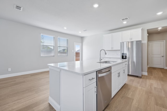 kitchen with appliances with stainless steel finishes, light wood-type flooring, sink, a center island with sink, and white cabinetry