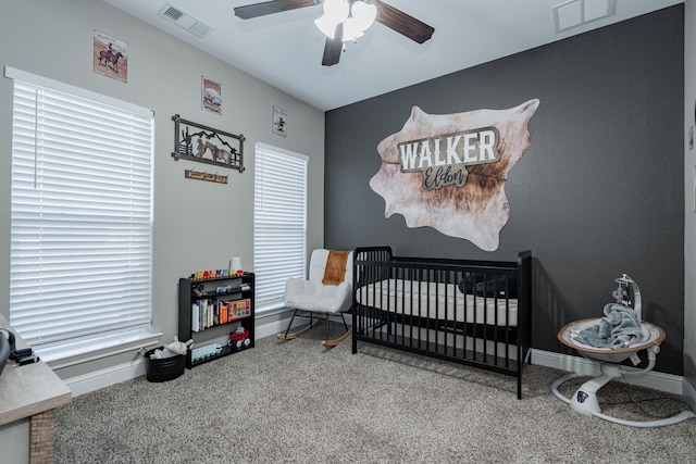 bedroom featuring carpet flooring, multiple windows, ceiling fan, and a nursery area