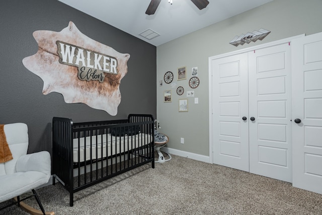 carpeted bedroom with a crib, a closet, and ceiling fan