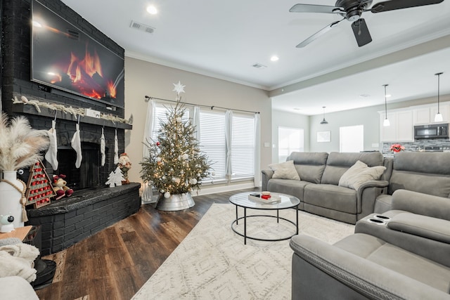 living room featuring ceiling fan, dark hardwood / wood-style flooring, ornamental molding, and a brick fireplace