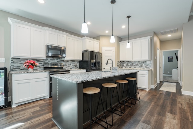 kitchen with a center island with sink, white cabinets, dark hardwood / wood-style floors, and appliances with stainless steel finishes