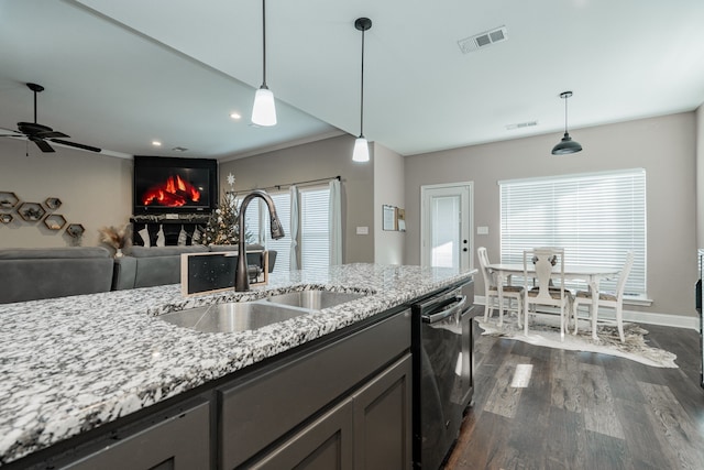 kitchen featuring a wealth of natural light, light stone countertops, sink, and dark wood-type flooring