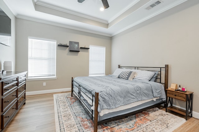 bedroom with a tray ceiling, light hardwood / wood-style flooring, ceiling fan, and ornamental molding