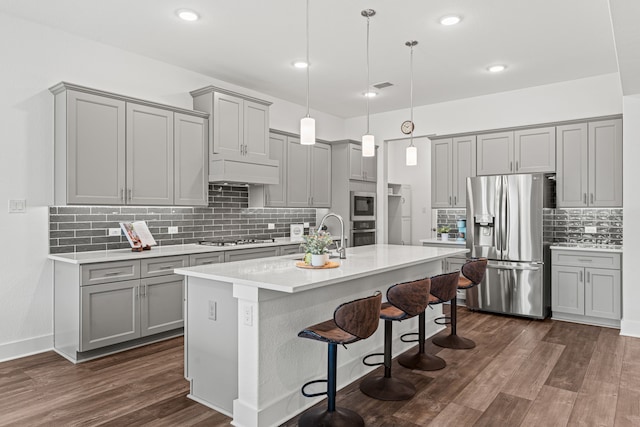 kitchen with sink, dark wood-type flooring, pendant lighting, a kitchen bar, and appliances with stainless steel finishes