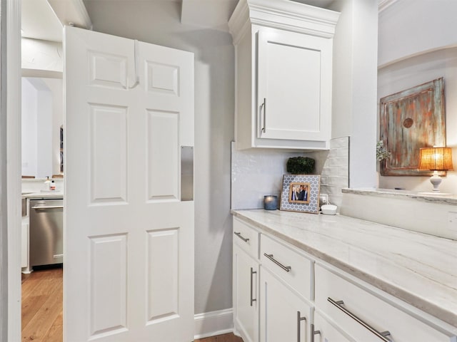 kitchen with dishwasher, backsplash, white cabinets, light hardwood / wood-style floors, and light stone counters