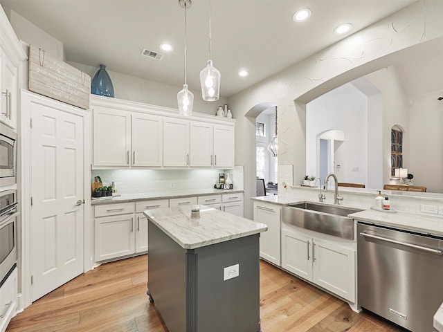 kitchen with sink, white cabinets, stainless steel appliances, and a kitchen island