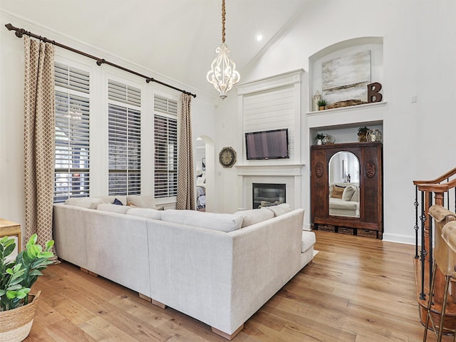 living room with a chandelier, lofted ceiling, and light wood-type flooring