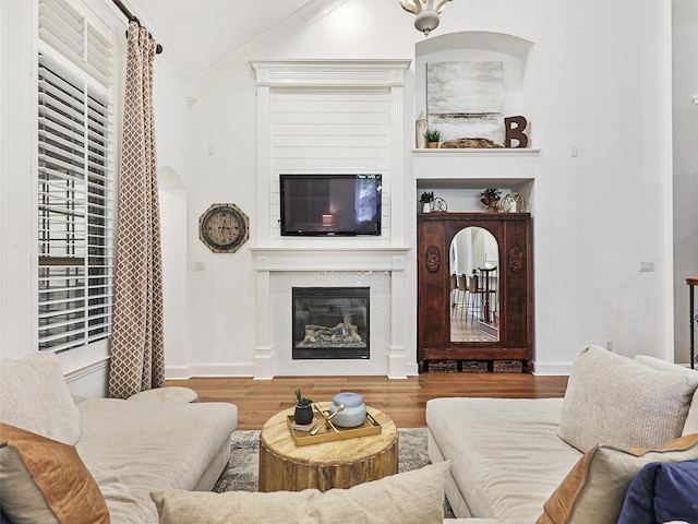 living room featuring wood-type flooring, ornamental molding, and vaulted ceiling