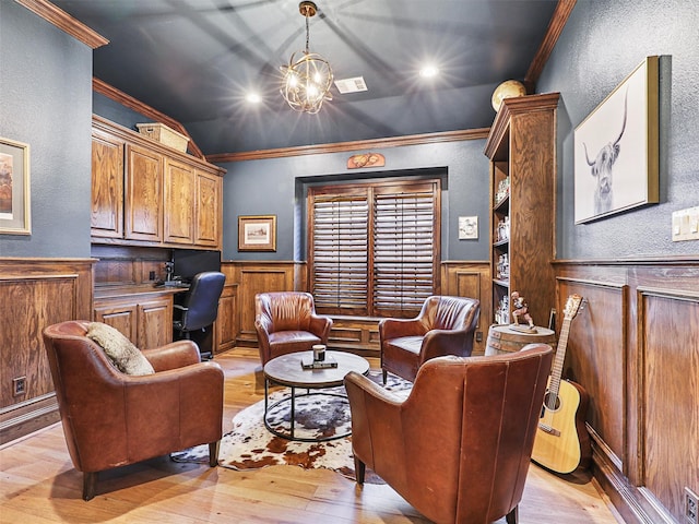 sitting room with a notable chandelier, light hardwood / wood-style floors, lofted ceiling, built in desk, and ornamental molding