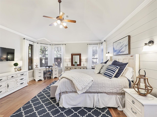 bedroom with ceiling fan, wood-type flooring, ornamental molding, and wooden walls