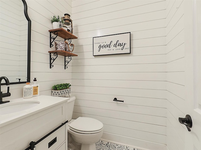 bathroom with vanity, wood walls, and toilet