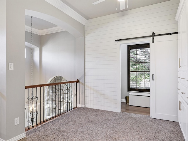 hallway featuring carpet floors, a barn door, and crown molding