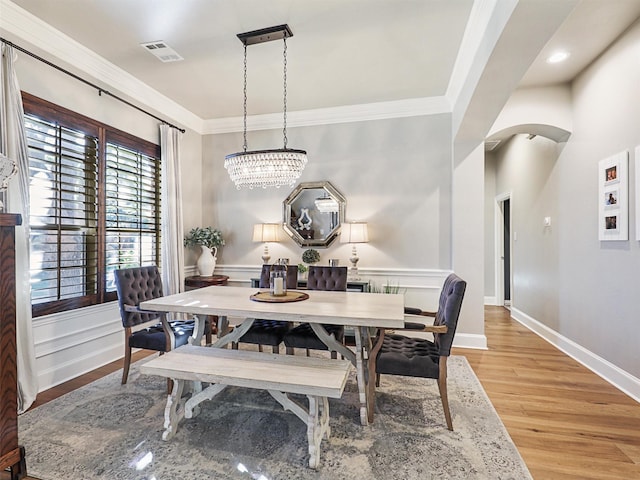 dining area featuring a notable chandelier, crown molding, and light hardwood / wood-style flooring