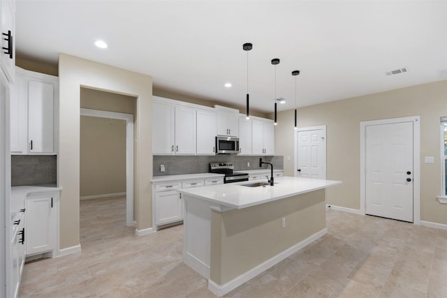 kitchen with decorative light fixtures, white cabinetry, stainless steel appliances, and an island with sink