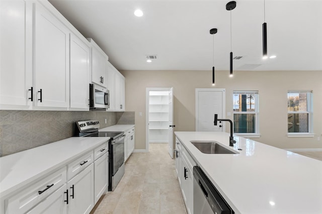 kitchen featuring white cabinets, sink, light hardwood / wood-style flooring, decorative light fixtures, and stainless steel appliances