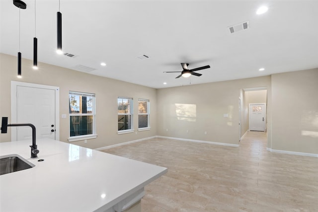 kitchen featuring decorative light fixtures, ceiling fan, and sink