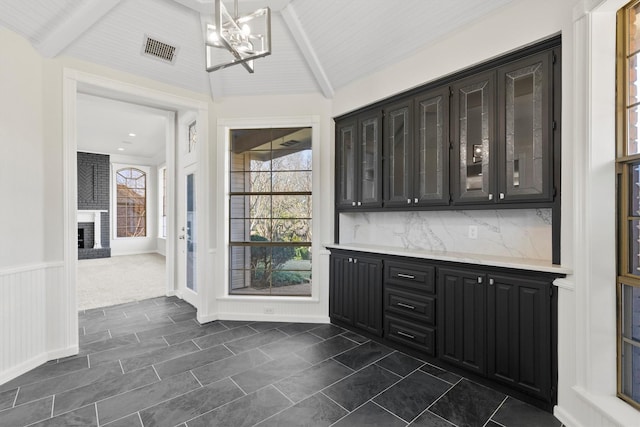 bar featuring lofted ceiling with beams, tasteful backsplash, an inviting chandelier, and a wealth of natural light