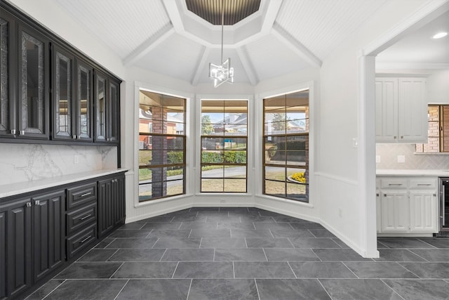 unfurnished dining area featuring wine cooler, vaulted ceiling, and an inviting chandelier