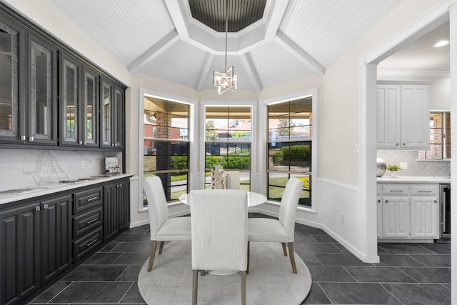 dining area featuring vaulted ceiling with beams, beverage cooler, a chandelier, and a healthy amount of sunlight