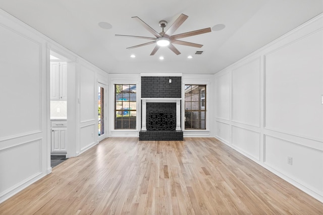 unfurnished living room featuring ceiling fan, a fireplace, and light wood-type flooring