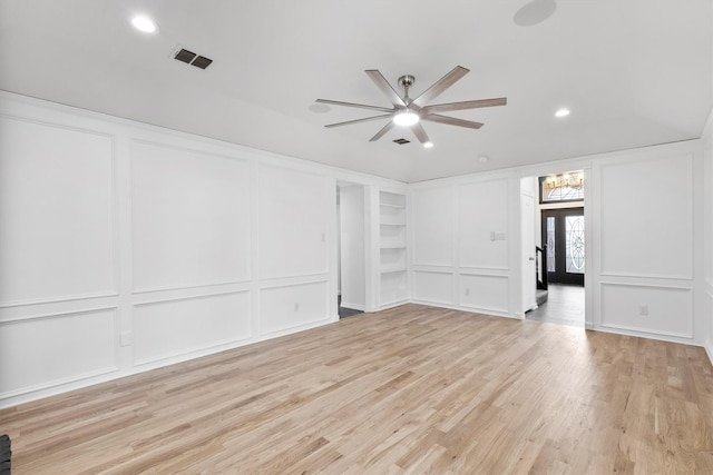 empty room with built in shelves, french doors, light hardwood / wood-style floors, and ceiling fan