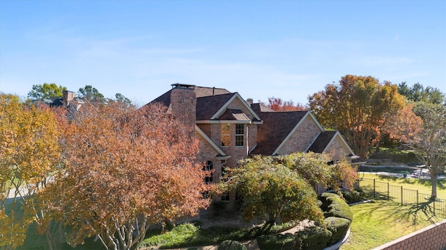 view of front of house with stone siding, a front lawn, a chimney, and fence