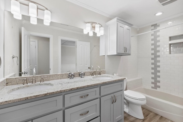 full bathroom with vanity, crown molding, wood-type flooring, toilet, and tiled shower / bath