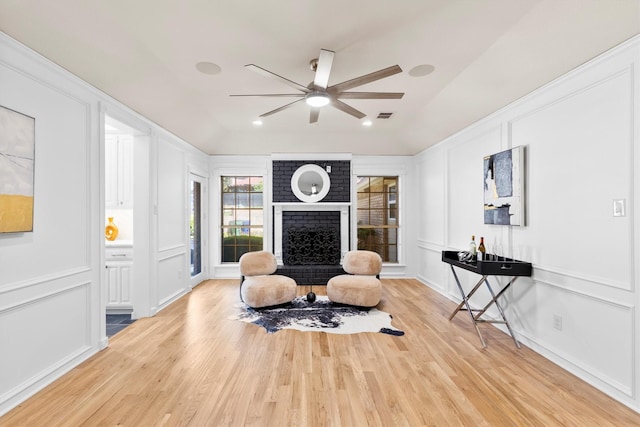 529 Bay Ct, Heath, TX 75032 - sitting room featuring a decorative wall, a ceiling fan, a fireplace, and light wood-type flooring