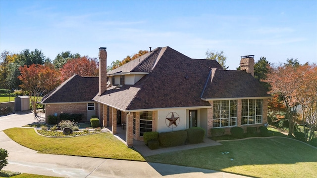 view of front of home featuring concrete driveway, brick siding, a chimney, and a front lawn