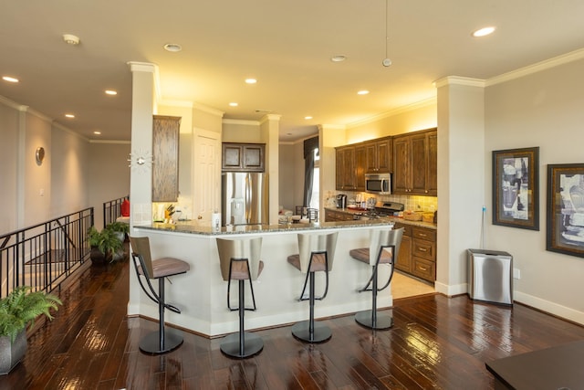 kitchen featuring a breakfast bar, kitchen peninsula, dark wood-type flooring, and appliances with stainless steel finishes