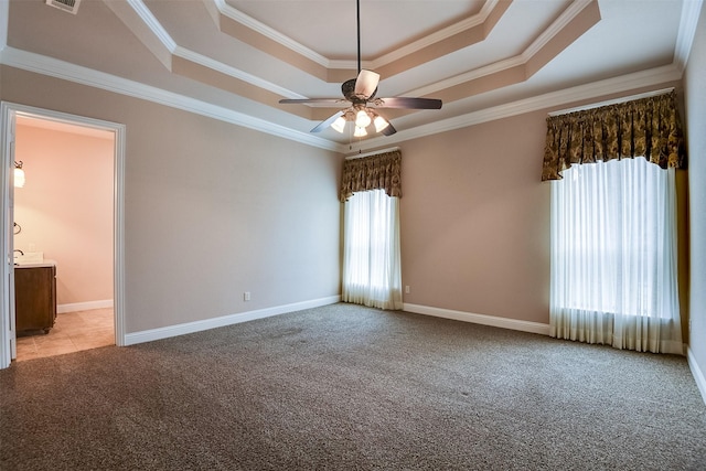 carpeted spare room with a raised ceiling, ceiling fan, and ornamental molding