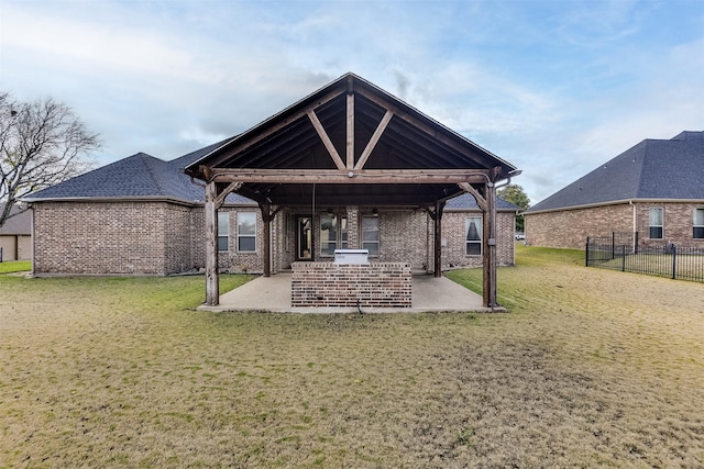 rear view of house featuring a lawn, an outdoor kitchen, and a patio