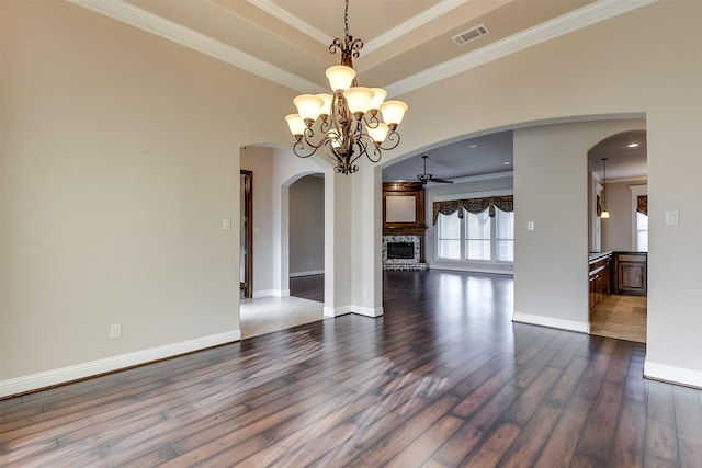 unfurnished dining area featuring hardwood / wood-style flooring, ceiling fan with notable chandelier, ornamental molding, and a fireplace