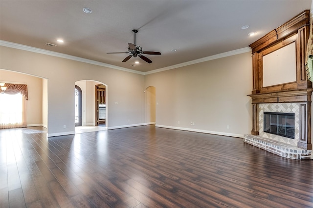 unfurnished living room featuring ceiling fan, a fireplace, dark hardwood / wood-style floors, and ornamental molding