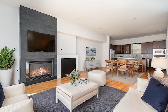 living room with a tile fireplace, light hardwood / wood-style floors, and sink