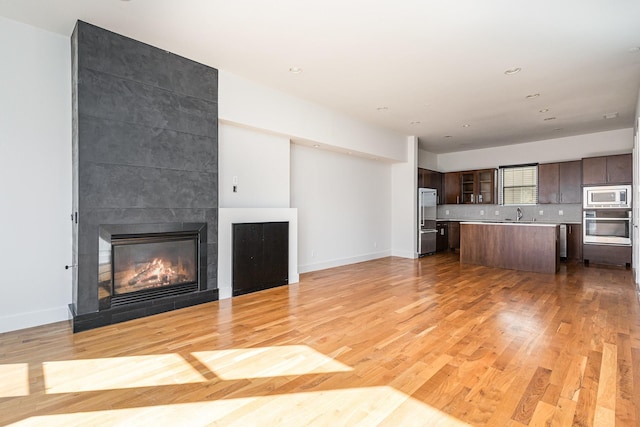 unfurnished living room featuring sink, a fireplace, and light hardwood / wood-style flooring