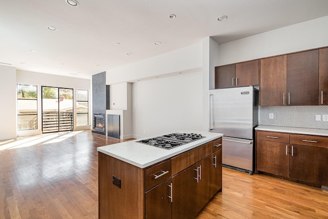 kitchen featuring a kitchen island, gas stovetop, high quality fridge, and light hardwood / wood-style flooring