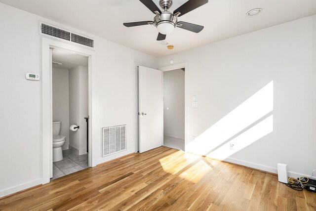 unfurnished bedroom featuring ceiling fan, wood-type flooring, and ensuite bath