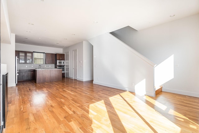 unfurnished living room with light wood-type flooring and sink