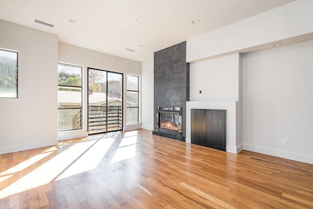 unfurnished living room with light hardwood / wood-style flooring and a tiled fireplace