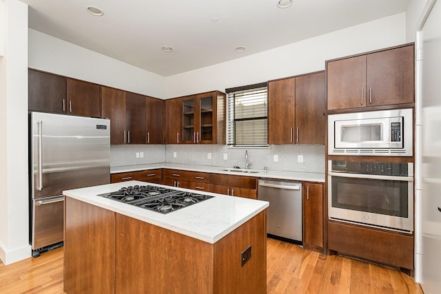 kitchen featuring backsplash, sink, light hardwood / wood-style floors, a kitchen island, and stainless steel appliances