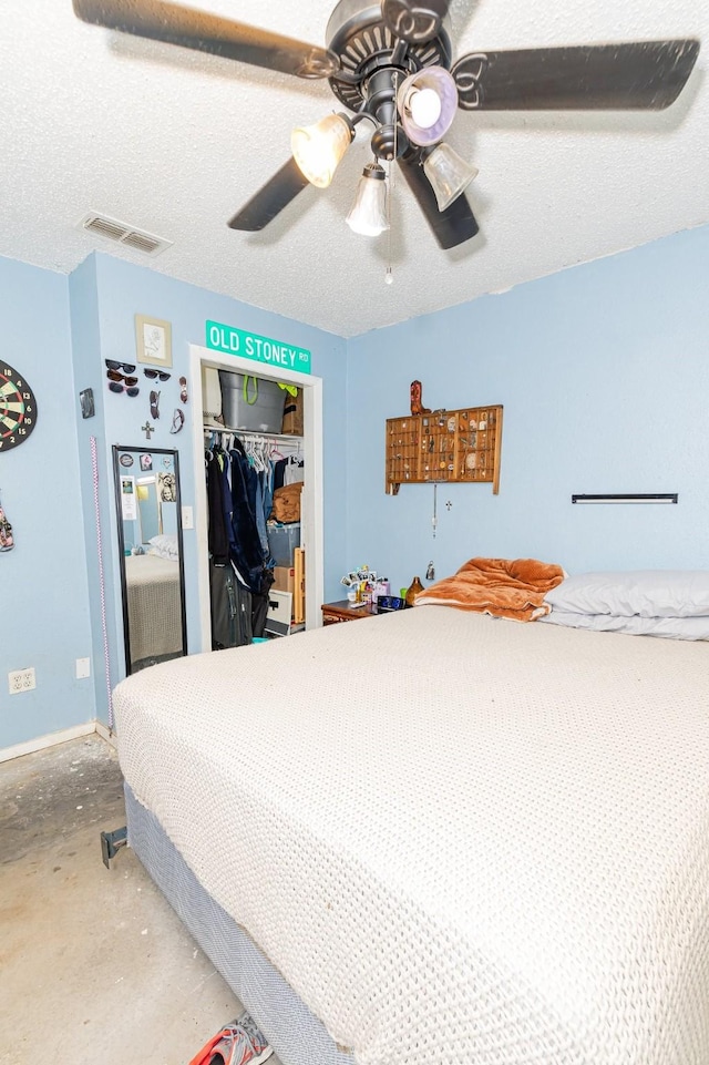 bedroom with ceiling fan, concrete floors, a textured ceiling, and a closet