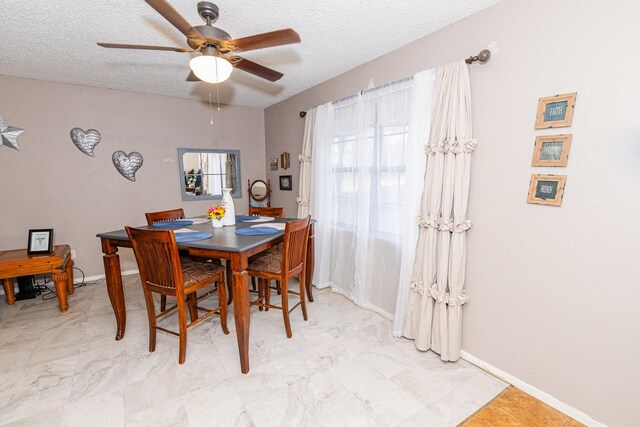 dining area with ceiling fan and a textured ceiling